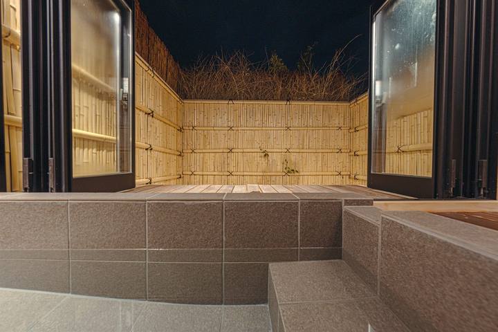 夜の半露天風呂。浴槽から、全開にした窓の先に竹垣で囲まれたデッキが見える
